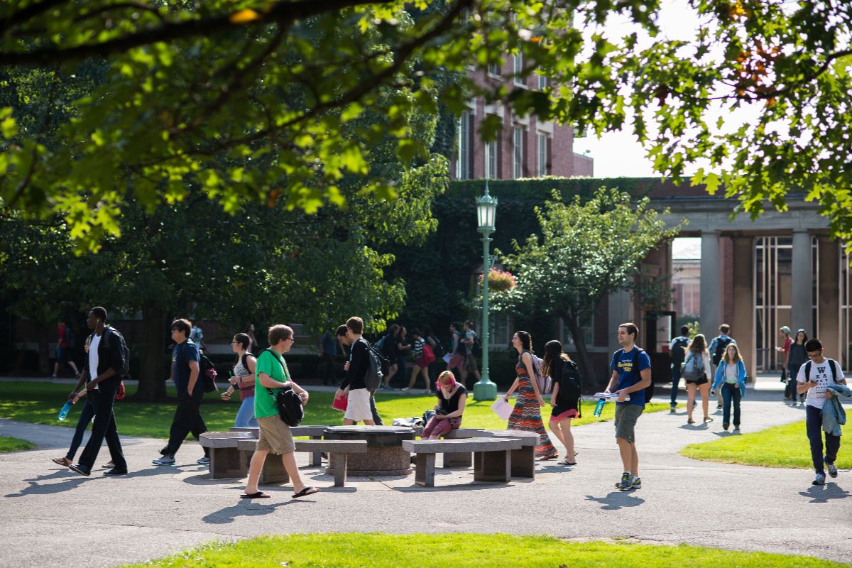 Students hurrying to across a sunny quad.