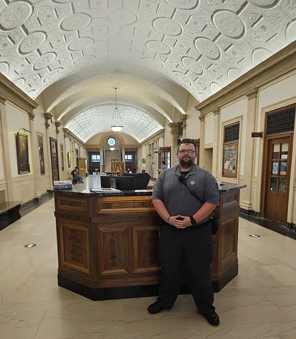A safety officer wearing a uniform stands in front of a welcome desk.
