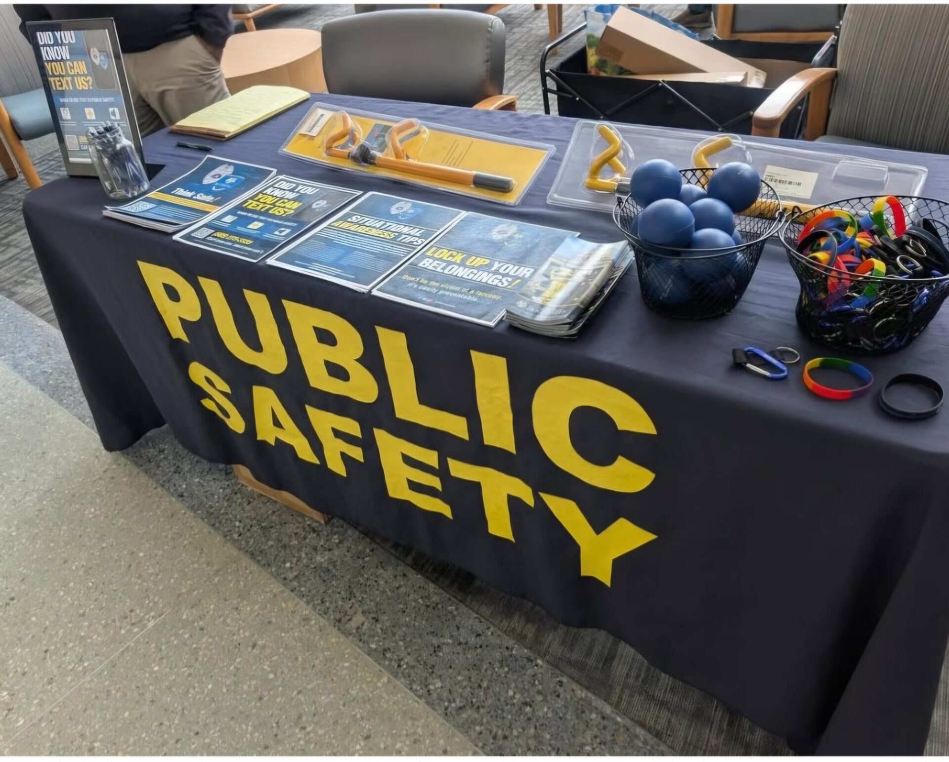 A table at an event with a University of Rochester Public Safety tablecloth and informational materials arranged on top.