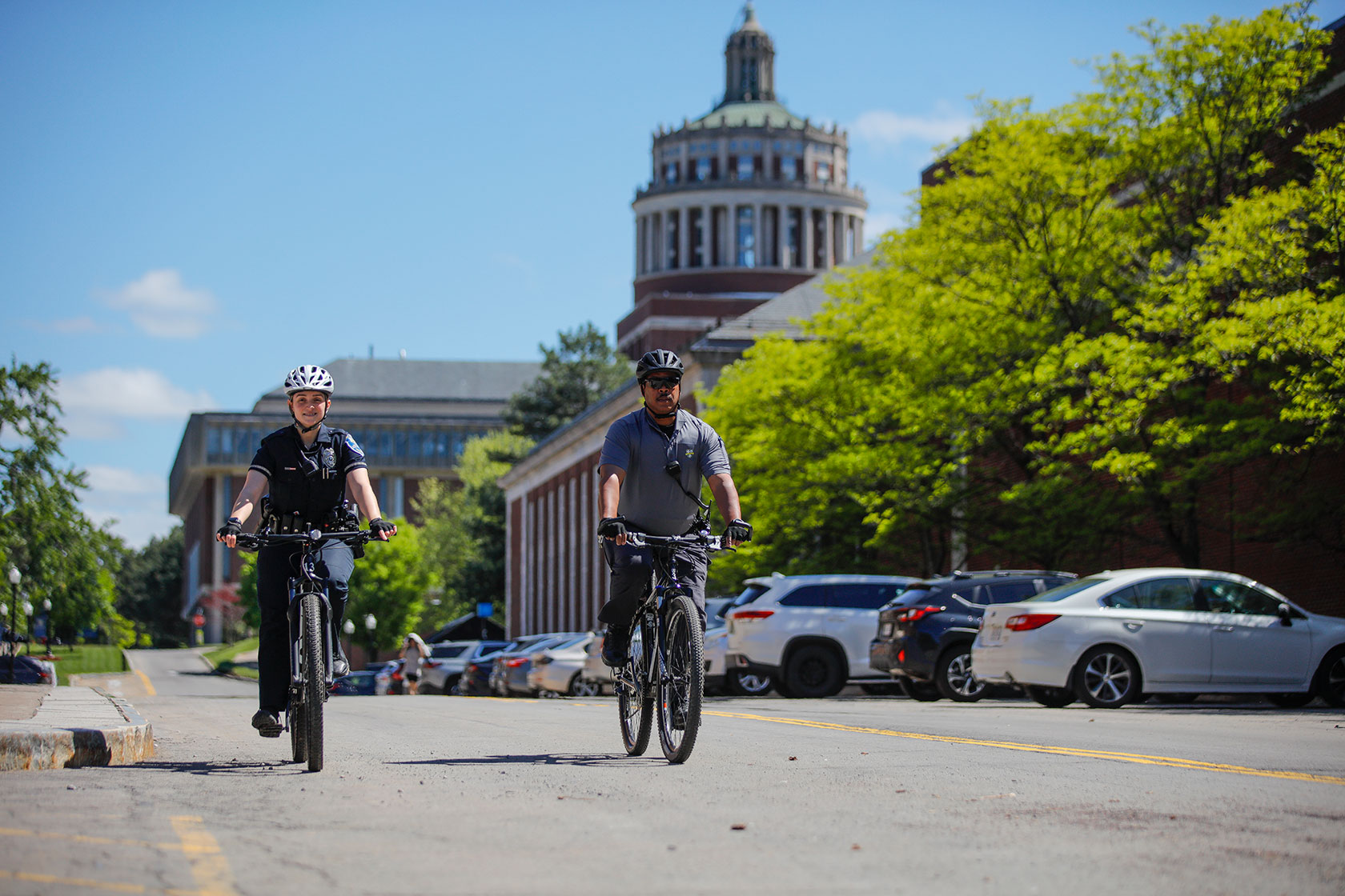 Two UR Department of Public Safety officers on bike patrol in front of Rush Rhees Library.