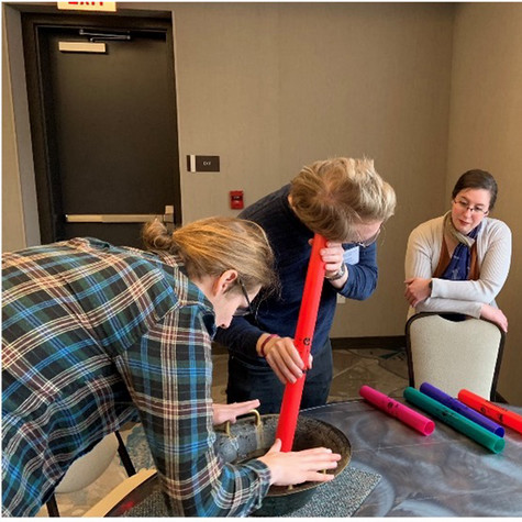 Two people conducting an experiment while a third person looks on.