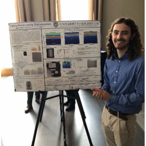 A researcher standing next to a postboard.