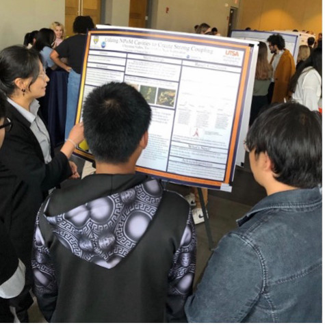 A group of people looking at a poster board.