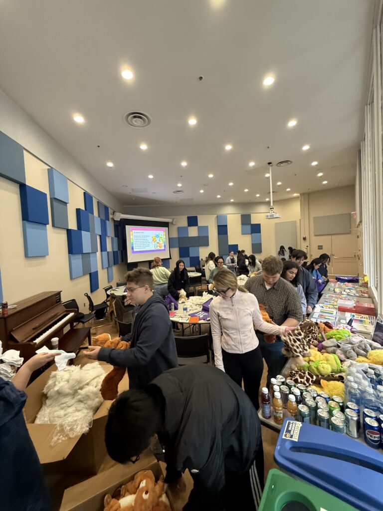 a photo of many people in a room stuffing fluff into a plushie for a Title IX self-care workshop