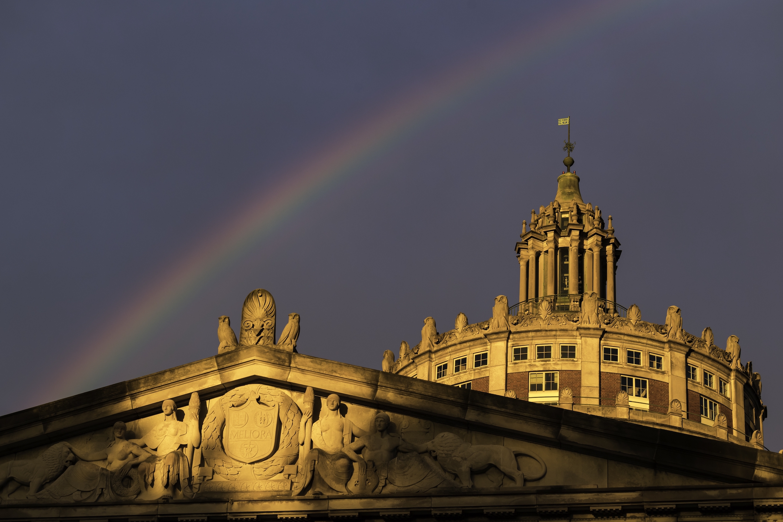 A rainbow appears over Eastman Quad and Rush Rhees Library at sunset