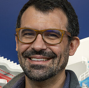 Portrait photo of Chris Smith in front of OMEGA Laser Facility mural.