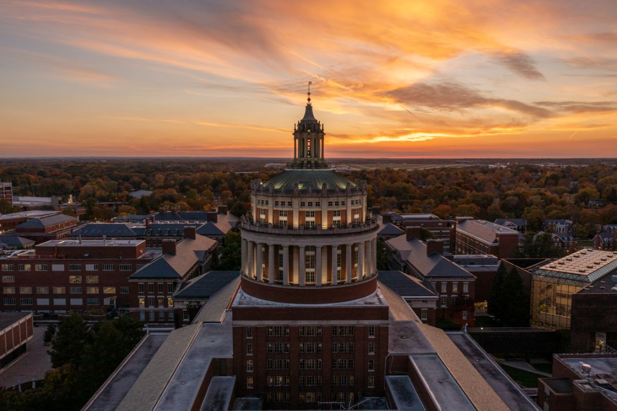 Tip of Rush Rhees library at night against an orange sky.