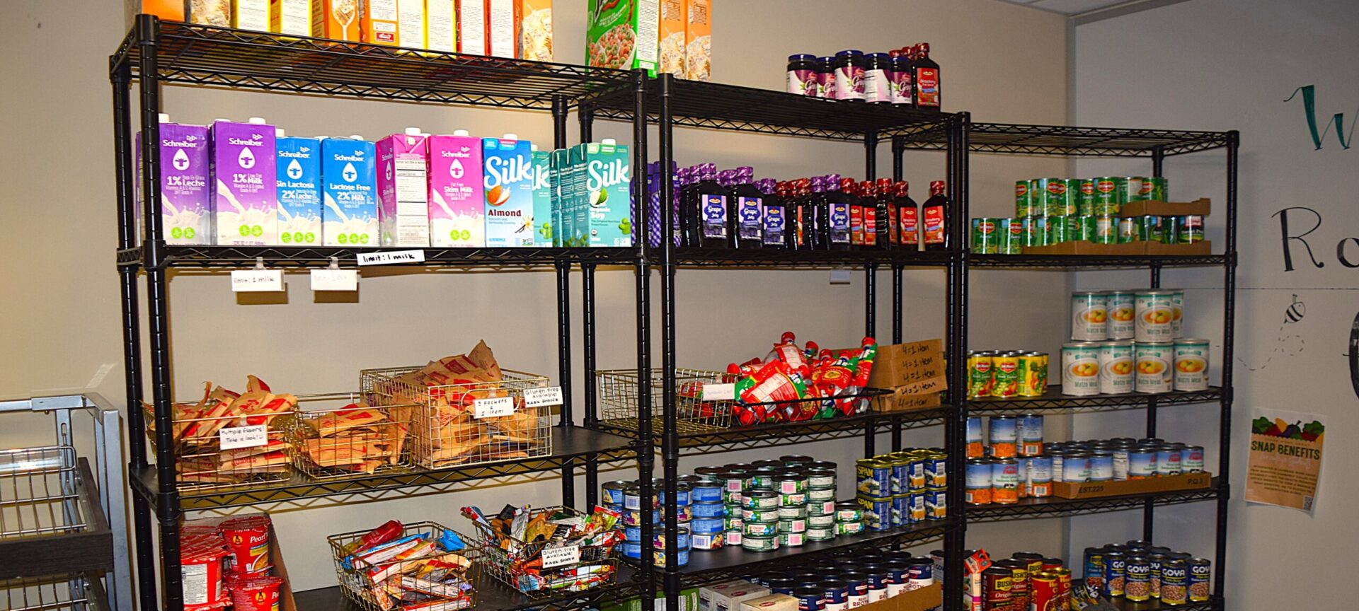 Metal shelves with non-perishable food items like cereals, shelf-stable milks, and canned goods.