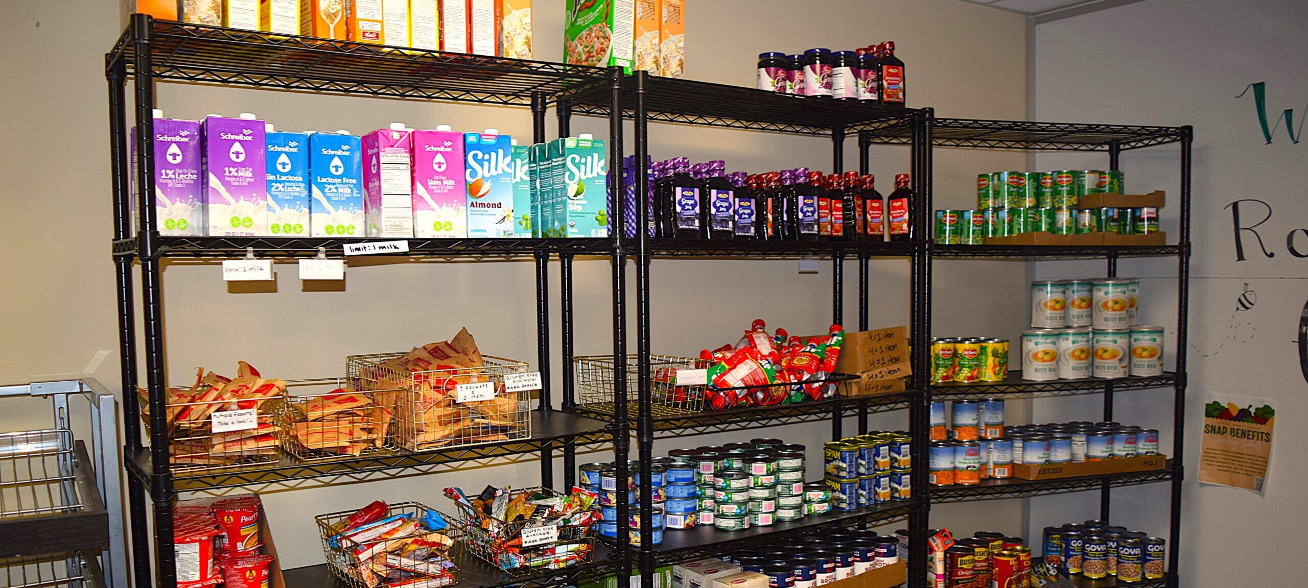 Metal shelves with non-perishable food items like cereals, shelf-stable milks, and canned goods.