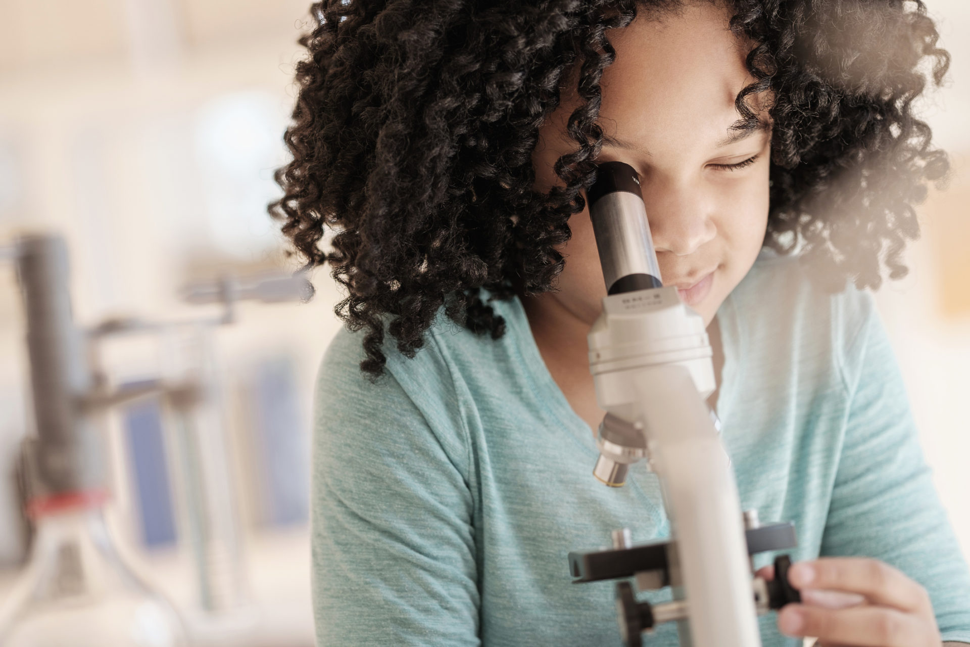 Girl using microscope in science classroom