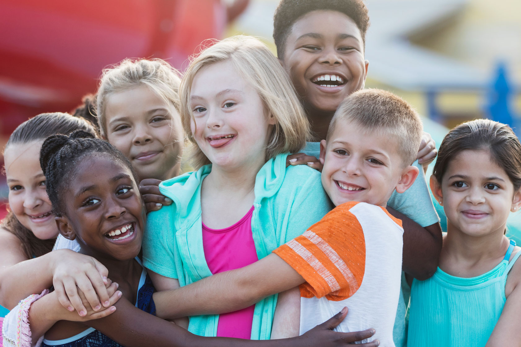 A group of children playing, hugging, and smiling