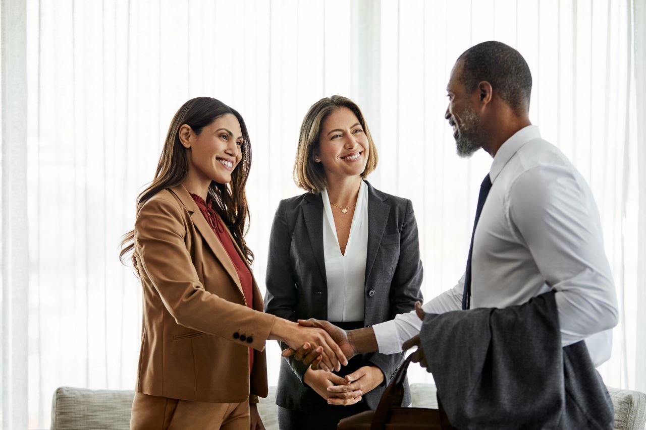 A group of business employees standing in a conference room and shaking hands