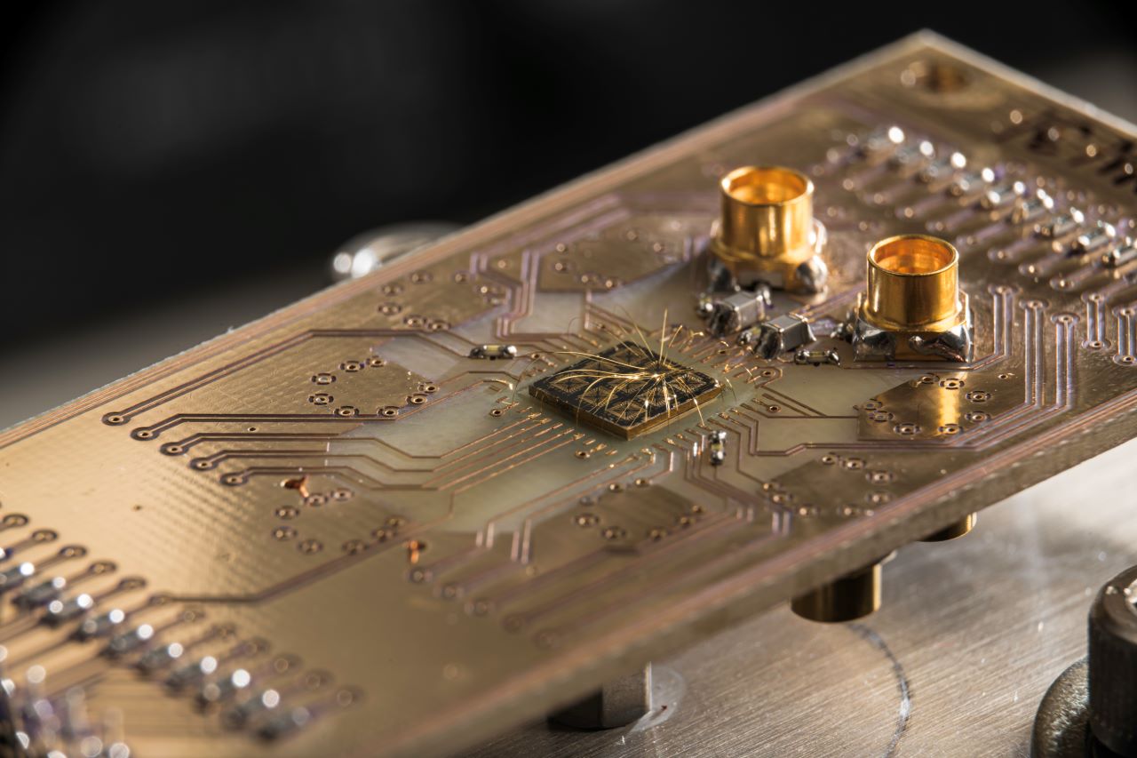 A quantum processor semiconductor chip is seen connected to a circuit board.