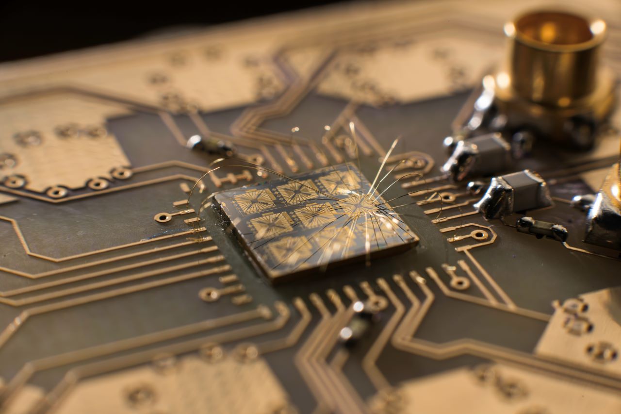 A quantum processor semiconductor chip is seen connected to a circuit board.