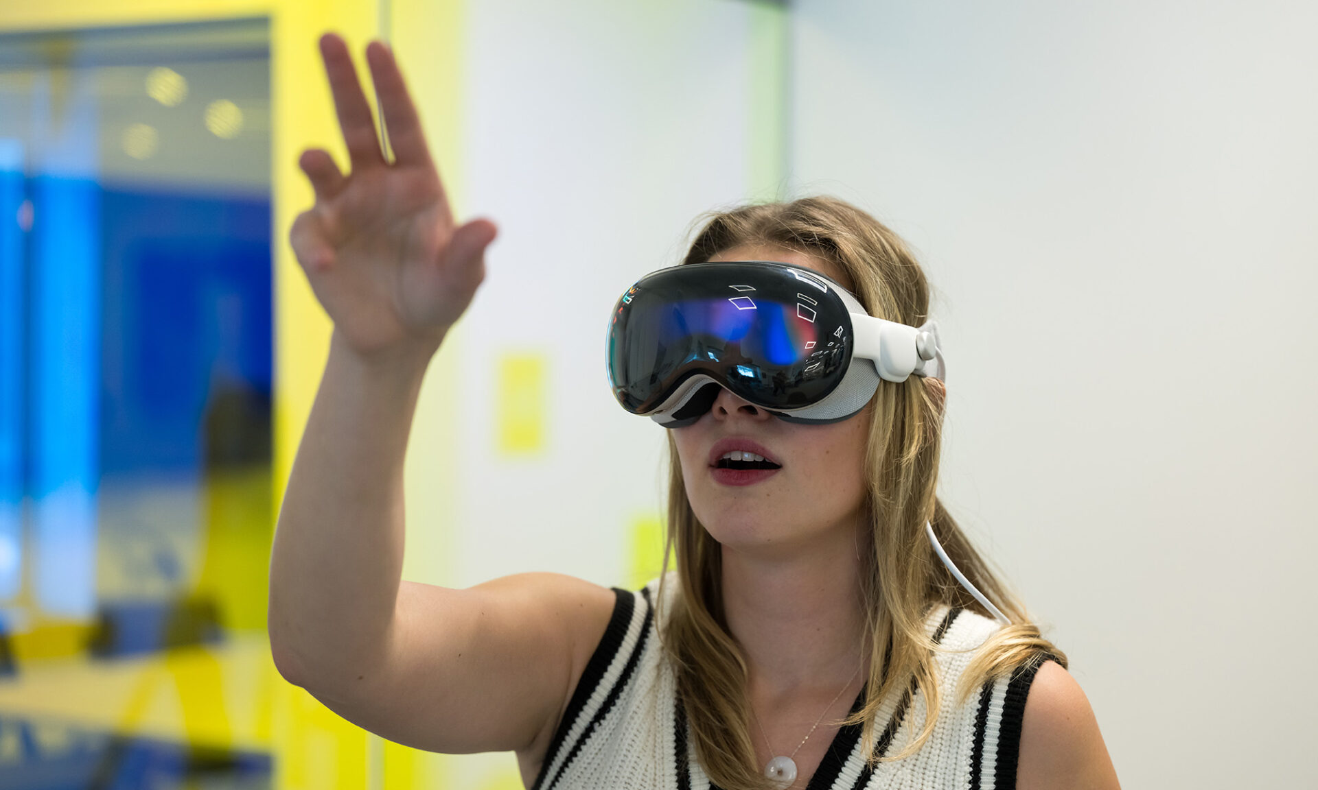 A student wearing AR/VR glasses while holding their hand up