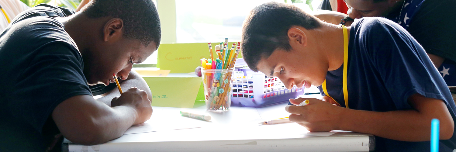 Two male students, heads down, working hard on assignments