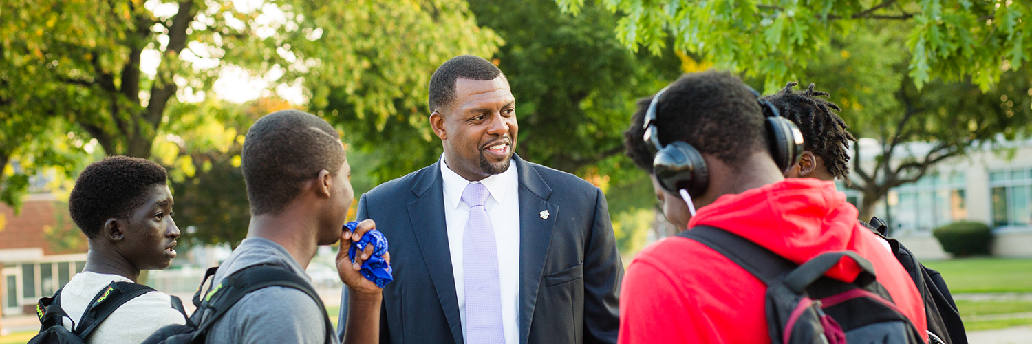 Superintendent Shaun Nelms talking with a group of male students outside