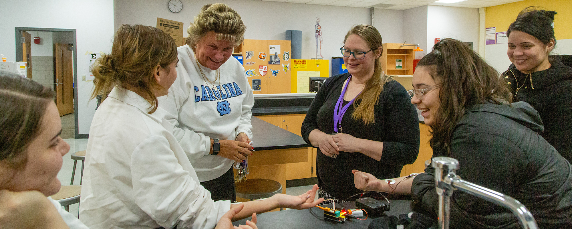 Principal and teachers watching kids do experiment in lab