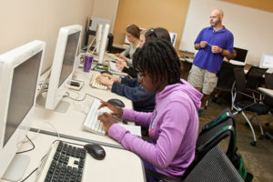 syudents working in computer lab with teacher looking on